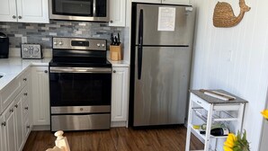 Una cucina moderna con mobili bianchi, elettrodomestici in acciaio inossidabile e un tavolo da pranzo in legno con un girasole.