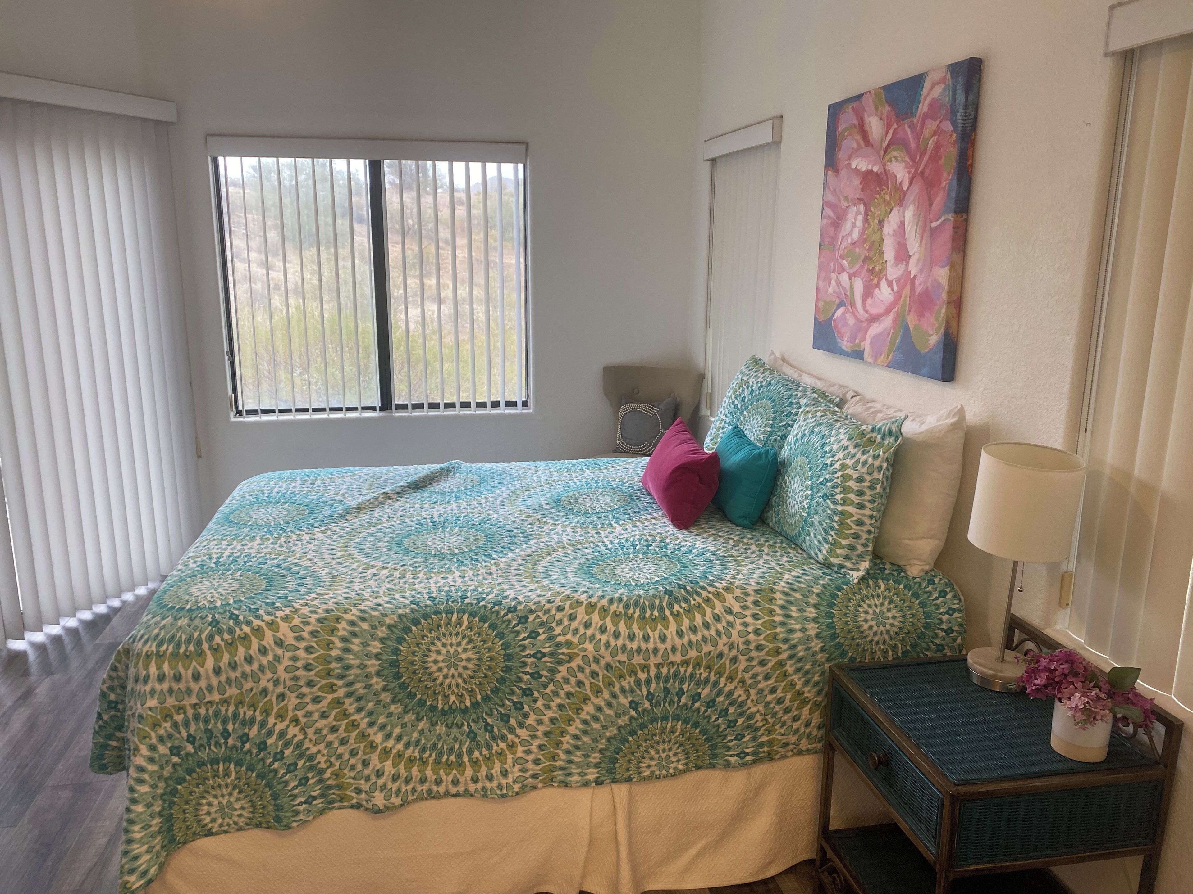 A bedroom with a bed, a nightstand, a lamp, and a window with blinds.