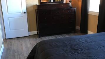 A bedroom with a bed, a dresser, a mirror, and a window with curtains.