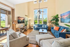 A spacious living room with a large window, a ceiling fan, and a view of the outdoors.
