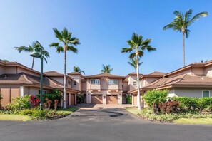 A residential complex with multiple two-story houses, a central driveway, and palm trees.