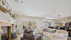 A spacious living area with a fireplace, a large sofa set, a dining table, and a view of the outdoors. - Stunning Lagoon & Harbour Town Golf Views! 2 Master Suites! (Hilton Head Island)