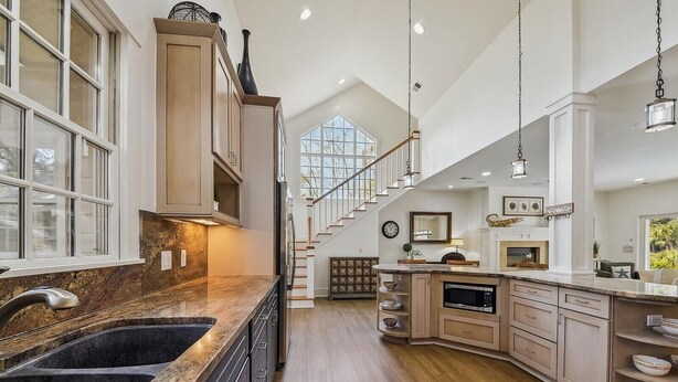A spacious kitchen with a central island, wooden cabinets, and a large window providing natural light. - Stunning Lagoon & Harbour Town Golf Views! 2 Master Suites! (Hilton Head Island)
