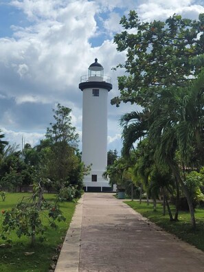 A lighthouse with a clear path leading to it, surrounded by greenery.
