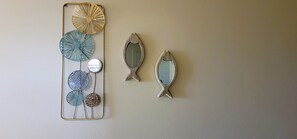 A wall with a decorative metal piece featuring circular and fish-shaped elements. - WaveView - 1 BR Condo w/ Ocean View - The Marilyn (Puntas Rincon)