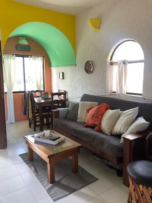 A cozy living room with a sofa, a coffee table, and a dining area with chairs and a table.
