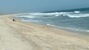 Una playa con arena y olas rompiendo sobre ella.