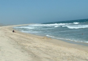 Uma praia com areal e ondas quebrando.