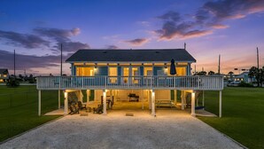 A two-story house with a covered porch and a fenced yard. - Beach Cottage with Big Yard & Ocean Views (Galveston)