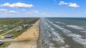 A coastal road with beachside buildings and ocean views. - Beach Cottage with Big Yard & Ocean Views (Galveston)