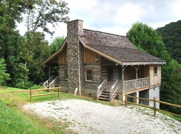 A rustic cabin with a stone chimney, wooden porch, and a gravel driveway. - Authentic Log Cabin in the Blue Ridge Mountains Family and Pet friendly (Newland)