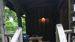 Une terrasse en bois avec une table de pique-nique et un barbecue, entourée de rampes et d’escaliers en bois.