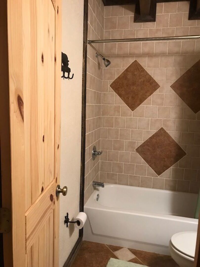 Un baño con bañera, inodoro y puerta de madera.