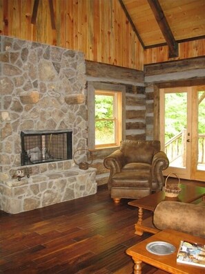 A cozy cabin interior with a stone fireplace, wooden walls, and a comfortable seating area. - Authentic Log Cabin in the Blue Ridge Mountains Family and Pet friendly (Newland)
