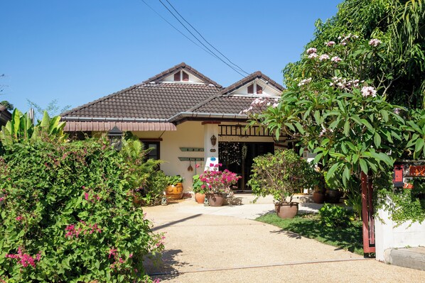 A traditional house with a tiled roof, a front porch, and potted plants.