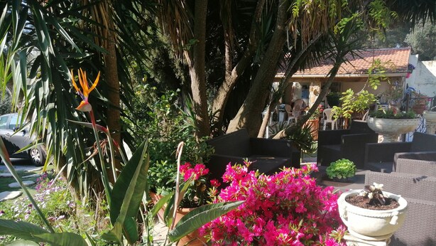 A patio area with outdoor seating, potted plants, and a building with a tiled roof in the background. - Villa Lysa studio in character house private pool (La Garde)