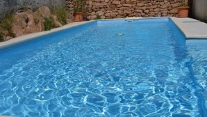 A rectangular swimming pool with clear blue water, surrounded by a stone wall and potted plants. - Villa Lysa studio in character house private pool (La Garde)