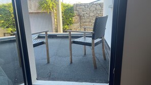 A patio area with a stone wall, a wooden table, and two chairs. - House / Villa - BRIGNOGAN PLAGESHouse with characterHouse with garden (Plounéour-Brignogan-Plages)