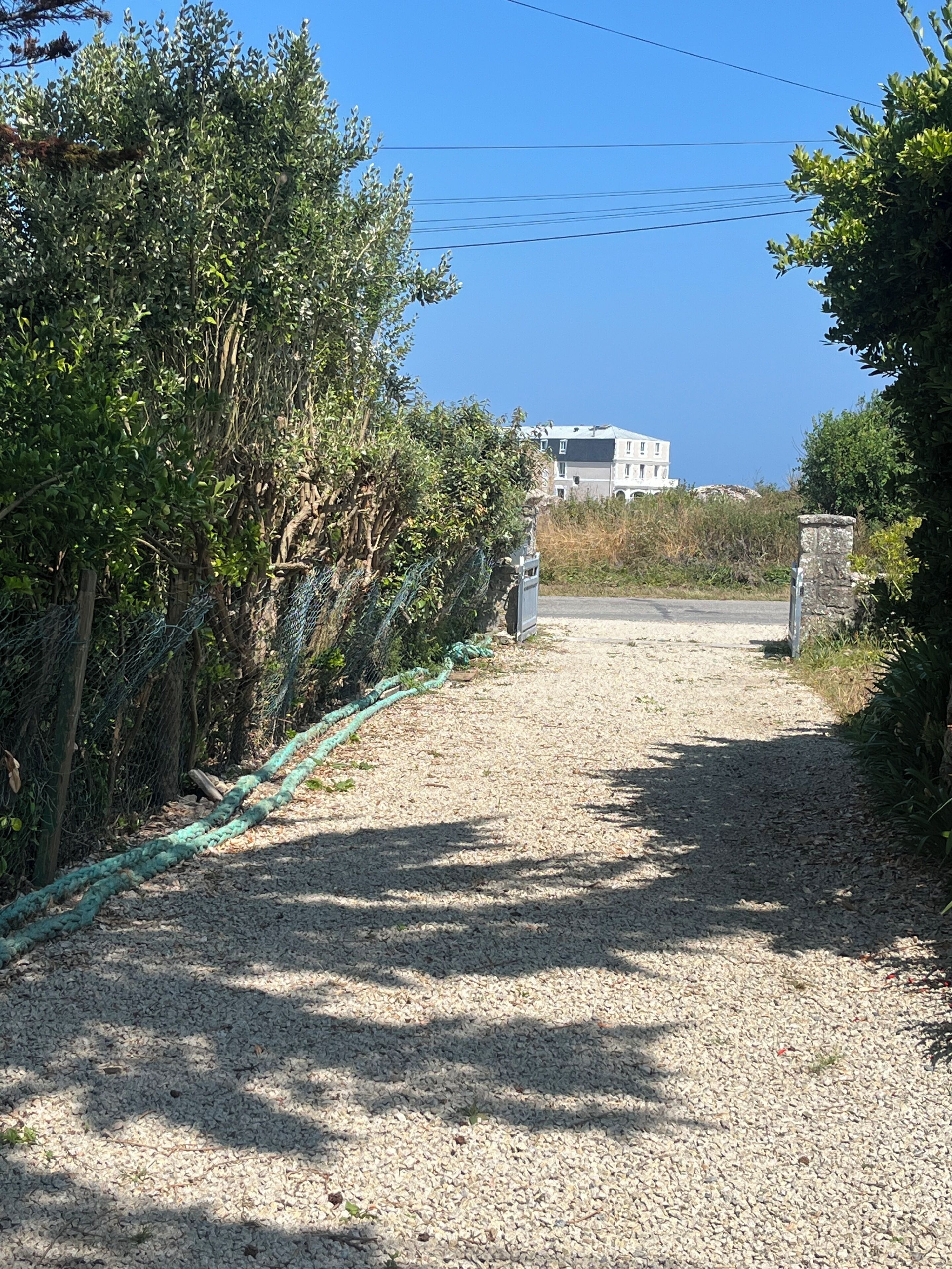 A gravel path leading to a building with a stone wall on one side.