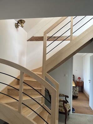 A wooden staircase with a modern design, leading to a room with a patterned sofa and a small table with a lamp. - House / Villa - BRIGNOGAN PLAGESHouse with characterHouse with garden (Plounéour-Brignogan-Plages)