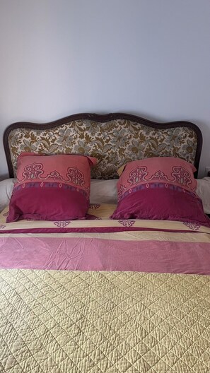 Un letto con un poggiatesta, due cuscini decorativi e una coperta trapuntata.
