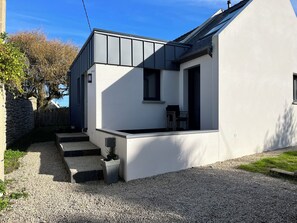 A modern house with a sloped roof, a small porch, and a gravel driveway.