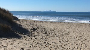 Une plage de sable fin, avec des vagues douces et un ciel dégagé.