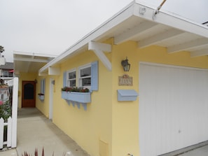 A yellow building with a white garage door, a mailbox, and a number sign.