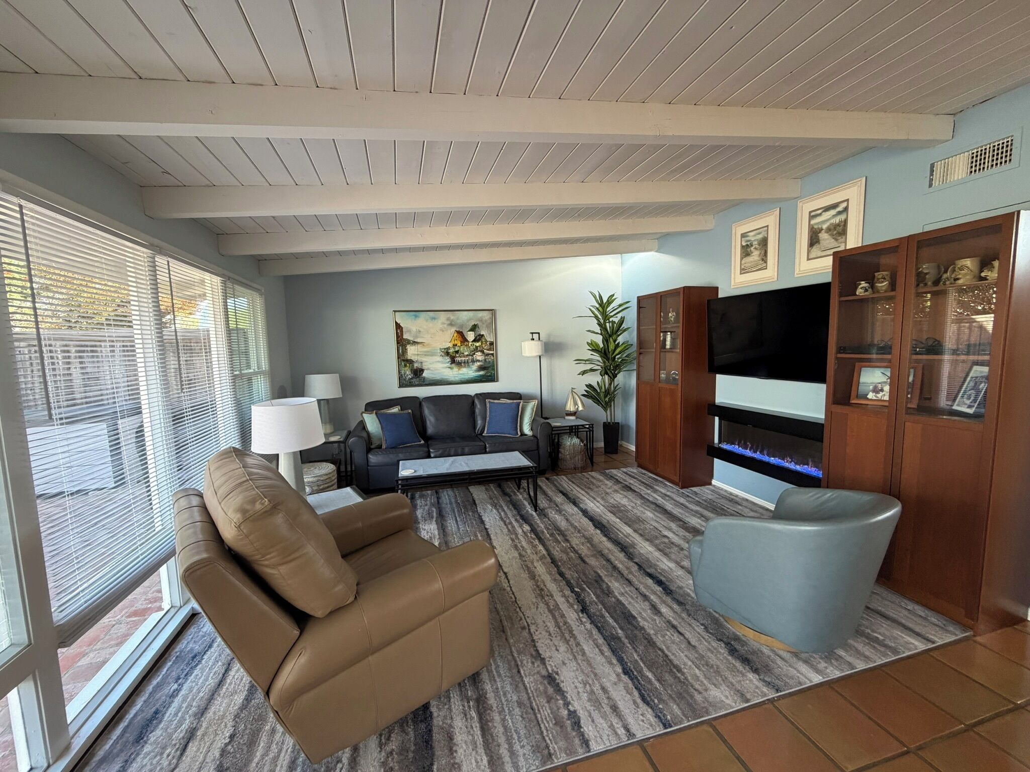 A living room with a sofa, a recliner, a TV, and a cabinet.