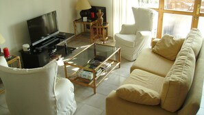 A living room with a sofa, armchairs, a coffee table, a TV, and a lamp.