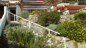 A hillside property with a stone staircase, a white railing, and a satellite dish.