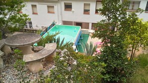 A courtyard with a swimming pool, stone seating, and surrounding greenery.