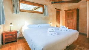 A hotel room with a large bed, wooden nightstands, a wardrobe, and a window with curtains. - Superior-Category Country Houses in a Natural Park. Nature and comfort. (Galaroza)