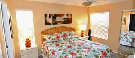A bedroom with a bed, nightstands, a ceiling fan, and a large mirror.