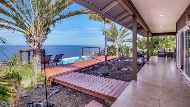 Ein überdachter Außenbereich mit Pool, Holzterrasse und Sitzgelegenheiten.