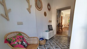 A room with a wicker chair, a small white table, and a signboard.