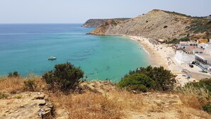 A coastal town with a beach, rocky terrain, and a boat in the water.