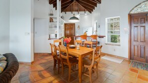Un'area pranzo con tavolo e sedie in legno, un lampadario e una finestra con cornice in pietra.