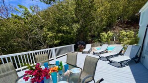 Una terrazza con un tavolo apparecchiato per mangiare, circondata da poltrone relax e vista su una piscina.