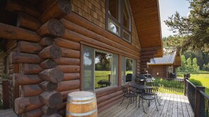Eine Blockhütte mit einer Terrasse, Sitzgelegenheiten im Freien und einem Grill.