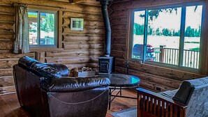 Ein Blockhaus-Interieur mit Kamin, Ledersofa und Holzboden.