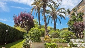 A garden with palm trees, a hedge, and a lamp post. - Big Apartment, Sea & Mountain views, private pool, close to amenities & IronMen  (Calella)