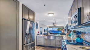 Una cocina moderna con electrodomésticos de acero inoxidable, una isla grande y vista al océano.