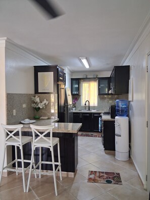 A kitchen with a dining area, a water dispenser, and a refrigerator.