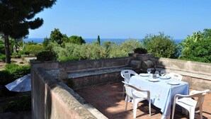 An outdoor dining area with a table set for two, overlooking a scenic view of the sea. - ancient 1700 Villa facing Eolie Island (Milazzo)