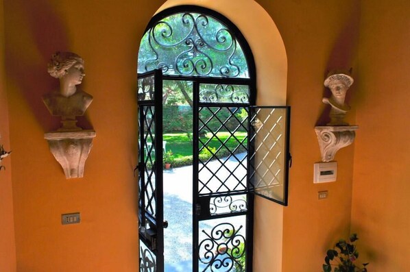 A doorway with a wrought iron gate, flanked by two bust sculptures.