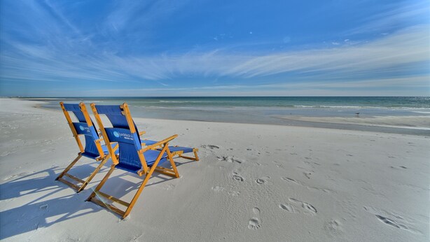 A beach with two blue and yellow beach chairs and footprints in the sand. - Southside of 30A, Gated beachfront pool sleeps 7 , 2 min walk to Rosemary, NEW ! (seacrest beach)