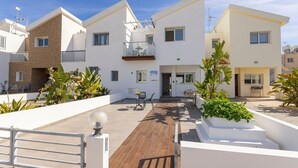 Ein modernes Wohngebäude mit einer Holzdachterrasse, weißen Wänden und Balkonen.