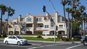 A multi-story residential building with a beige facade, balconies, and palm trees in the background. - STEPS FROM THE BEACH - HUNTINGTON CONDO - BEAT THE HOTEL COSTS (Huntington Beach)