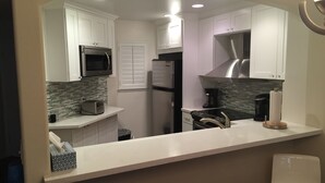 A modern kitchen with white cabinets, a stainless steel refrigerator, a microwave, and a coffee maker. - STEPS FROM THE BEACH - HUNTINGTON CONDO - BEAT THE HOTEL COSTS (Huntington Beach)